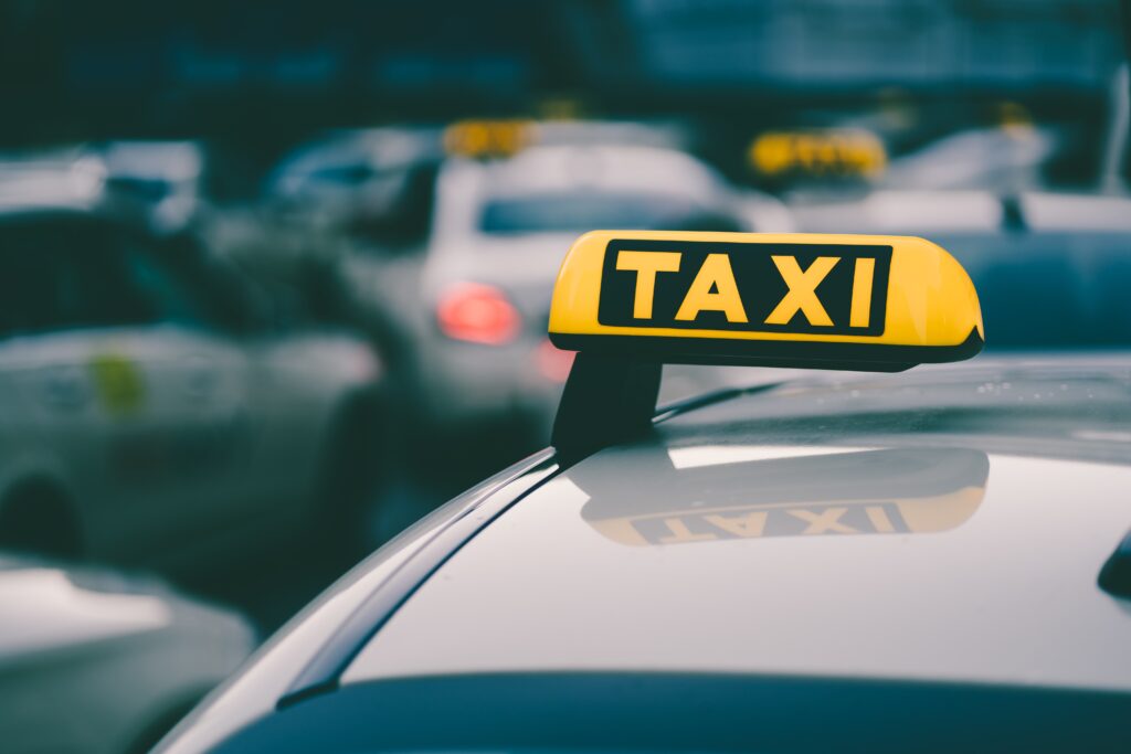 A selective focus shot of a yellow taxi sign in a traffic jam